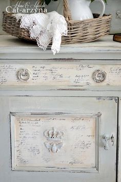 an old dresser is painted white and has lace on the drawer top, along with a wicker basket