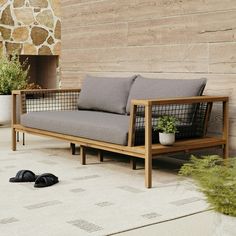 a couch sitting on top of a cement floor next to a planter filled with flowers