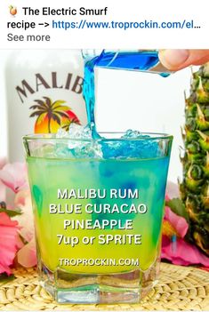 a person pouring blue curacao into a glass with pineapple on the side