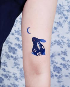 a small tattoo on the arm of a person with a blue rabbit and flower design