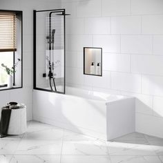 a bathroom with white tile and black trim on the walls, along with a large bathtub