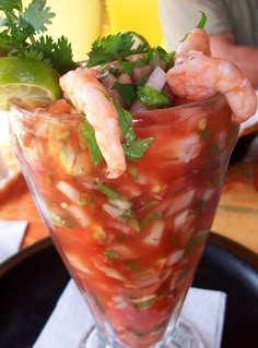 a glass filled with shrimp and vegetables on top of a table