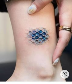 a woman's leg with a tattoo design on the back of her thigh, which is covered in blue water droplets