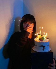 a person taking a photo with their cell phone in front of a cake that has candles on it