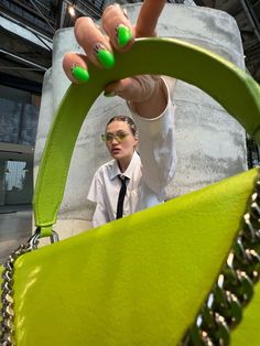 a woman with green nail polish holding onto a bag that is shaped like a handbag