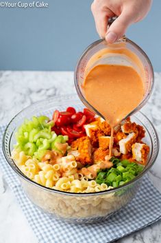 someone pouring dressing into a bowl of pasta salad