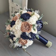 a bridal bouquet with blue, white and peach flowers on a wooden table in front of a mirror