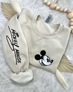 Cozy up in a bit of magic with our enchanting, Magical Autograph crewneck sweater. This sweater has a soft blended interior and features an embroidered face of the beloved Mr. Mouse on the left side of the chest and his autograph alongside the right sleeve. It could not get any cuter than this! ✦Sweater design features two embroidered locations. ✦Choose your preferred colored crew! ✦Interested in a different character? Head over to our "All Crewnecks" tab or type 'Magical Autograph Crewneck' in the search bar to see the other characters! ✦Want to pair this sweater with our mouse ears? Browse our ear selection to find your favorite match! Beige Embroidered Crew Neck Sweater, Embroidered Cream Long Sleeve Sweatshirt, Cream Embroidered Long Sleeve Sweatshirt, Cream Sweatshirt With Embroidered Logo For Winter, Cream Crew Neck Sweatshirt For Winter, Cream Cotton Sweater With Embroidered Logo, Embroidered Cream Cotton Sweater, Cream Embroidered Cotton Sweater, Cream Cotton Embroidered Sweater