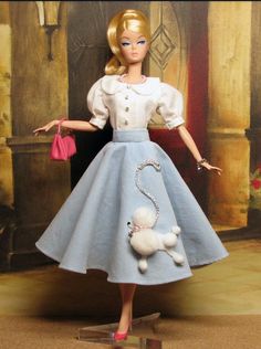 a barbie doll dressed in blue and white with a poodle on it's head