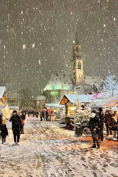 people are walking in the snow near buildings