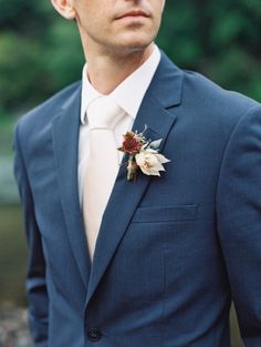 a man wearing a suit and tie with a boutonniere on his lapel