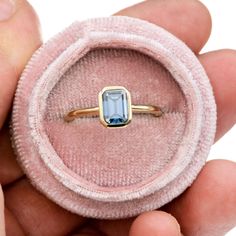 a person holding a ring with a blue stone in it's center and inside