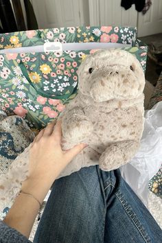 a person holding a stuffed animal in front of a flowered purse on a couch