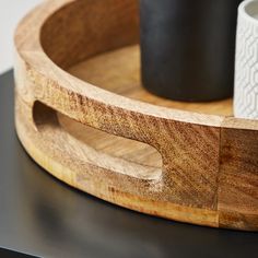 a wooden tray with two mugs on it and one cup in the other side