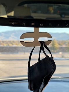 a black purse hanging from the side of a car window with mountains in the background