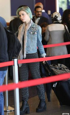 a woman with blue hair is standing in an airport