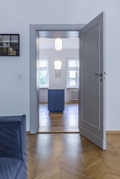 an open door leading into a living room with hard wood flooring and white walls