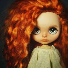 a close up of a doll with red hair and blue eyes wearing a white dress