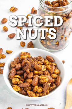 a white bowl filled with spiced nuts next to a wooden spoon and glass jar