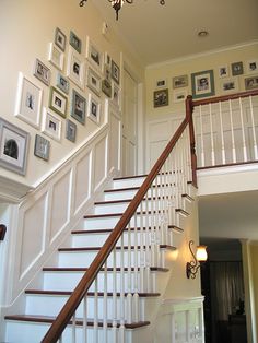 a staircase with pictures on the wall and chandelier