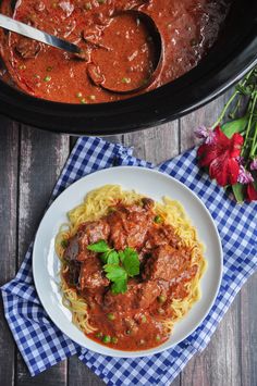 a plate of spaghetti with meat sauce and flowers on the side, next to a pot of pasta