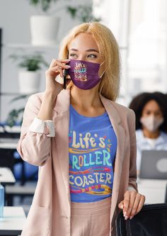 a woman wearing a purple face mask while talking on her cell phone in an office