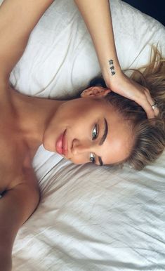 a beautiful young woman laying on top of a bed