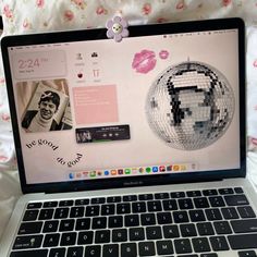 a laptop computer sitting on top of a bed covered in pink and white sheets,