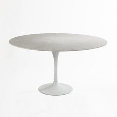 an oval marble dining table with white pedestals, on a white background in the shape of a tulip