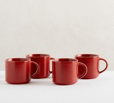 four red coffee mugs lined up in a row