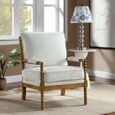 a white chair sitting next to a lamp on top of a table