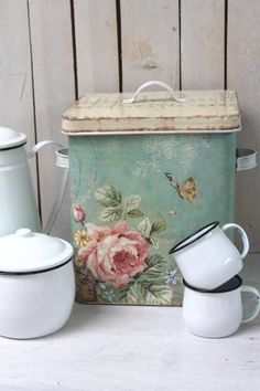 a set of three white dishes and a teapot on a wooden table next to a painted box