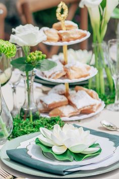 a table topped with plates filled with food and flowers on top of each plate covered in greenery