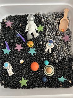 a white container filled with lots of black beans covered in magnets and stars next to a wooden spoon