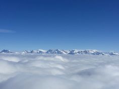 the view from an airplane looking down on some mountains and clouds in the foreground