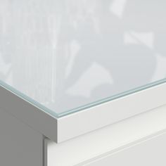 a close up view of a glass top on a white cabinet with silver trimmings