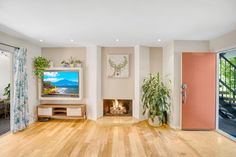 a living room with hardwood floors and a flat screen tv mounted on the wall above a fire place