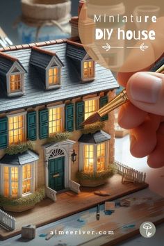 A DIY miniature house project, with a hand applying some paint to the shutters of a miniature mansion on a crafting table Diy House Craft, Making Miniature Houses, Building Miniature Houses, Doll House Miniatures Diy, Diorama Ideas Diy, Miniature Houses Diy How To Make, Mini House Craft, Miniature Houses Diy