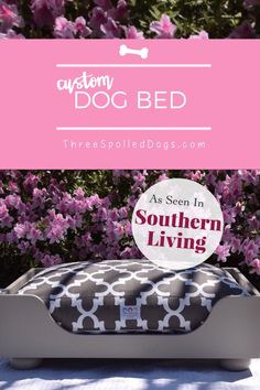 a dog bed that is sitting in front of some purple flowers and bushes with the words,