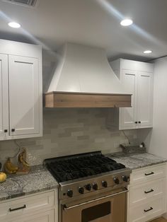 a stove top oven sitting inside of a kitchen next to white cupboards and drawers