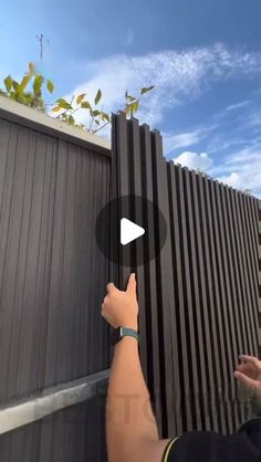 a man is holding onto the side of a fence with his hand and pointing at it