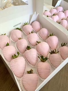 a box filled with pink strawberries sitting on top of a wooden table next to other boxes