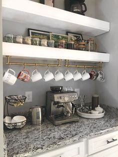 a kitchen counter with coffee cups hanging from the shelves and mugs on the shelf