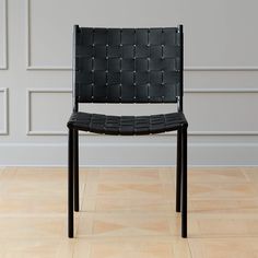 a black chair sitting on top of a hard wood floor next to a white wall