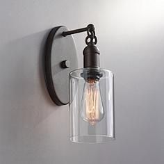 a light that is on the wall next to a glass lamp shade and metal frame