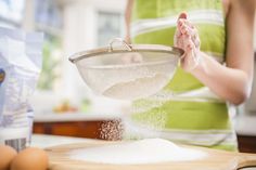 a woman is sprinkling flour into a bowl