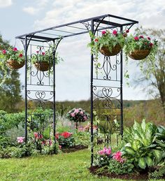 an outdoor garden with lots of flowers and plants hanging from it's sides,