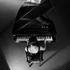 a woman sitting at a piano with her hands on the keyboard and looking down from above