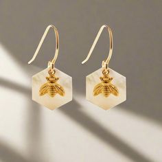 These earrings feature luminous 12mm Mother of Pearl hexagons as honeycomb with a tiny bee. They hang from 14k gold fill ear wires. Designed and assembled in Sonoma California. Honey Bee Earrings, Sonoma California, Bee Earrings, Honey Bee, Ear Wires, Honeycomb, Mother Of Pearl, Gold Filled, Honey