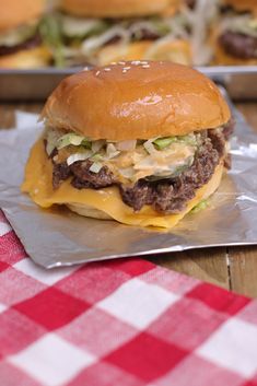 a cheeseburger with lettuce and other toppings sits on aluminum foil